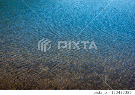 夏の浅瀬の水面と水紋、澄んだ水と底の土のテクスチャ 133483389