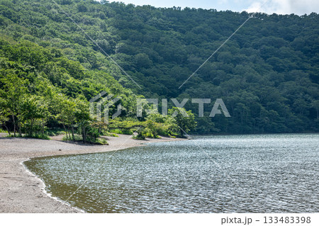 群馬県赤城山の小沼の湖畔と砂浜、夏の青空と濃い緑の山 133483398