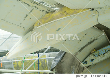 Repair work on the tail wing of an aircraft during maintenance at an airport facility early in the morning 133484810