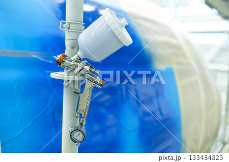 Spray gun setup for industrial painting in a large manufacturing facility during daytime Spray gun setup for industrial painting in a large manufacturing facility during daytime 133484823