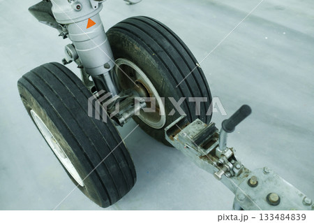 Exposed aircraft landing gear wheels showing detailed tire tread and hydraulic components on a maintenance floor in an aircraft hangar during daytime 133484839