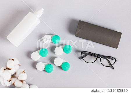 Concept of choosing between glasses and contact lenses on a table top view Concept of choosing between glasses and contact lenses on a table top view 133485329