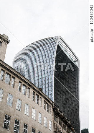 Modern Curved Glass Skyscraper Above Historic City Buildings Modern Curved Glass Skyscraper Above Historic City Buildings 133485343