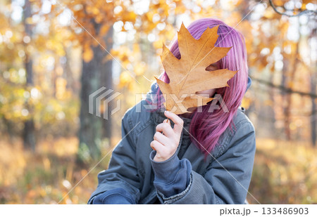 Young woman hiding face with autumn leaf Young woman hiding face with autumn leaf 133486903