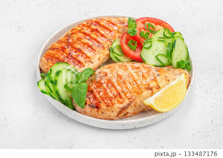 Grilled chicken breast served with fresh cucumber, tomato slices, basil and lemon on a white plate top view Grilled chicken breast served with fresh cucumber, tomato slices, basil and lemon on a white plate top view 133487176