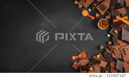 Assorted chocolate pieces with nuts and spices arranged on a dark textured background with generous copy space for branding, menus, or dessert advertising 133487187
