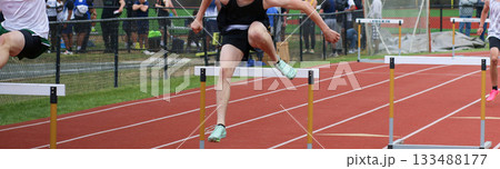 High School Athlete Competes in Hurdle Race During Track Event 133488177
