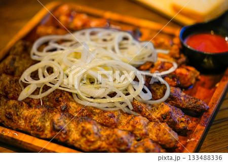 Tasty dish barbecue of meat with onion and sauce on plate 133488336