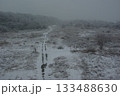 雪の積もった河川敷に車の通った跡が残ってどこまでも続いている。 133488630