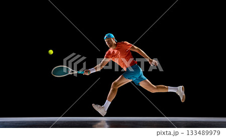 Male tennis player running to reach fast ball during match moment 133489979