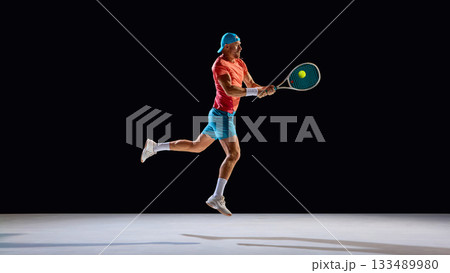 Male tennis player jumping for midair shot with precision and intensity 133489980