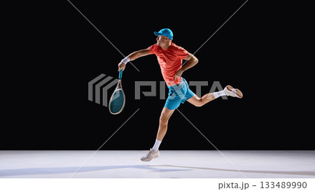 Energetic tennis player hitting forehand in jump with confident expression 133489990