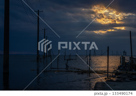 千葉県久津間海岸、夕焼けに染まる海中電柱のドラマチックな風景 133490174