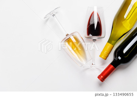Wine glasses with red and white wine and bottles lying on white background Wine glasses with red and white wine and bottles lying on white background 133490655