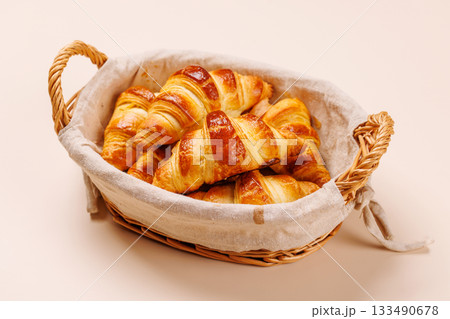 Freshly baked croissants in wicker basket on light background 133490678
