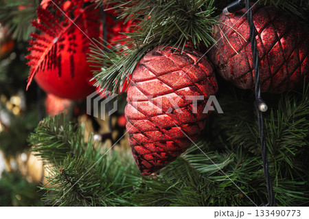 Christmas tree with red ball as pine cone and lights garland. Xmas card. Close up. Winter. Outdoors. 133490773