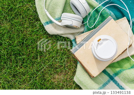 Books, coffee, and headphones on a sunny lawn 133491138