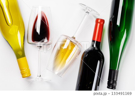 Wine glasses with red and white wine and bottles lying on white background Wine glasses with red and white wine and bottles lying on white background 133491169