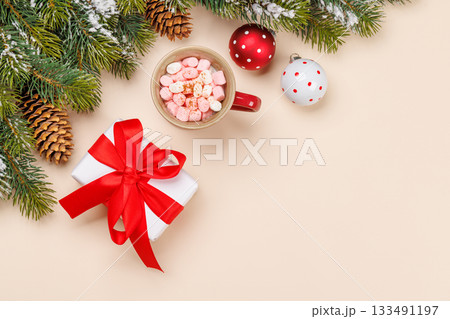 Gift box, cup with marshmallows, snowy fir branches 133491197