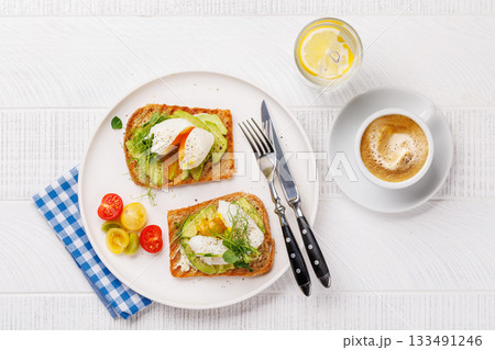 Delicious avocado toasts topped with perfectly cooked poached eggs 133491246