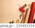 Christmas gift wrapping with red and brown wrapping paper, rope, labels, scissors, candy canes on beige backdrop. Copy space. 133491334