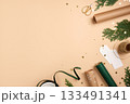 Gift wrapping background. Paper rolls, gift tag, and gold stars on beige table. Copy space for holiday text or design. 133491341
