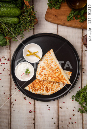 Grilled chicken quesadilla on black plate serving 133491819