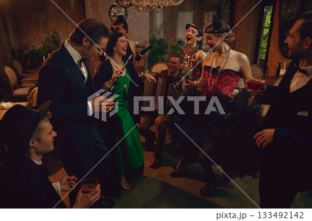 Retro group laughing and dancing with accordion player during lively vintage party night Retro group laughing and dancing with accordion player during lively vintage party night 133492142