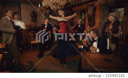 Glamorous retro dancer in red corset performing for stylish friends in vintage club Glamorous retro dancer in red corset performing for stylish friends in vintage club 133492181