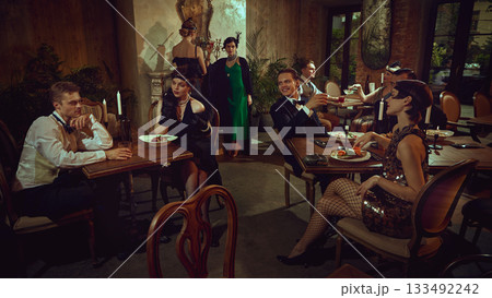 Retro dinner gathering with elegant friends celebrating in warm vintage atmosphere Retro dinner gathering with elegant friends celebrating in warm vintage atmosphere 133492242