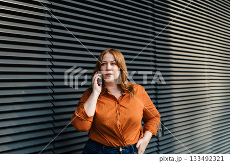 Curvy adult woman making phone call outdoors. Curvy adult woman making phone call outdoors. 133492321