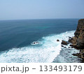 A Panoramic View of Ocean Waves Crashing Against a Cliffside with Rocky Shores Under a Clear Sky 133493179