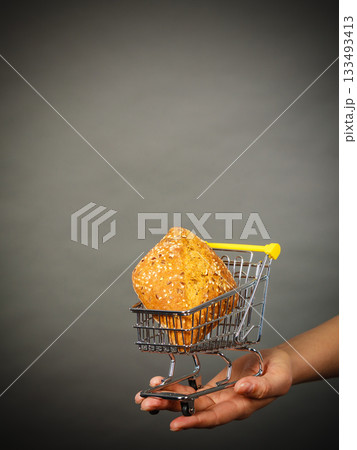 Woman hand holding shopping cart with bread Woman hand holding shopping cart with bread 133493413