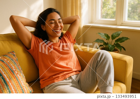 Woman Relaxing on Yellow Sofa with Arms Behind Head in Sunlit Living Room Featuring Plants and Window 133493951