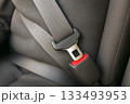 Close-Up of Gray Car Seat Belt with Red Release Button Attached to Fabric Seat in Vehicle Interior 133493953