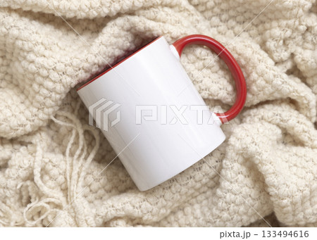 White accented coffee mug with red handle on beige plaid top view, boho mockup 133494616