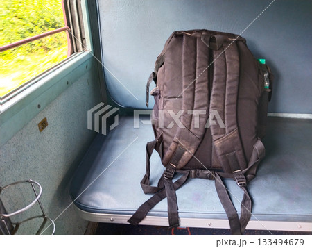 black backpack made of hard clothes on a blue seat of train coach. indian train window black backpack made of hard clothes on a blue seat of train coach. indian train window 133494679
