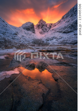 Vibrant orange and red sunset illuminating snow-covered peaks 133495306