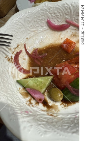 Empty salad plate with fork showing remnants of tomato, cucumber, and pickled onions Empty salad plate with fork showing remnants of tomato, cucumber, and pickled onions 133496424