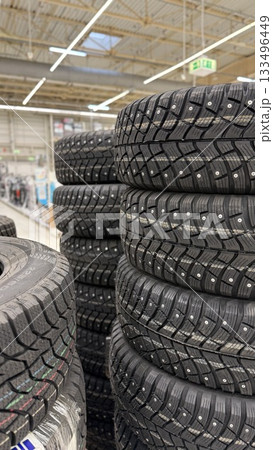 Tire stacks in store showcasing winter tires with visible treads and spikes under fluorescent lighting 133496449