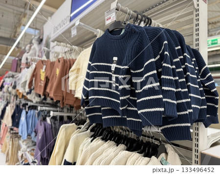 Childrens clothing on display in retail store aisle, showcasing various styles and colors 133496452