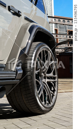 Luxury SUV parked in urban area on a sunny day showcasing custom wheels and tires Luxury SUV parked in urban area on a sunny day showcasing custom wheels and tires 133496795