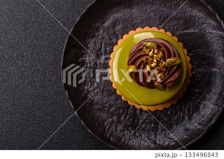 Pistachio cake or tart topped with green mousse with nuts and fruit filling. Pistachio pie 133496843