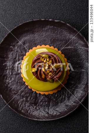 Pistachio cake or tart topped with green mousse with nuts and fruit filling. Pistachio pie 133496844