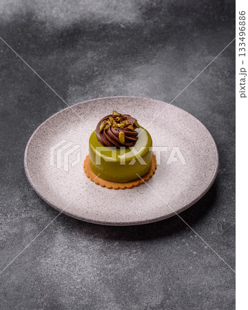 Pistachio cake or tart topped with green mousse with nuts and fruit filling. Pistachio pie 133496886