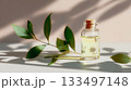 Natural essential oil with green leaves on a light background in calming sunlight 133497148