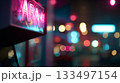 Neon sign illuminates street scene at night with colorful bokeh lights 133497154