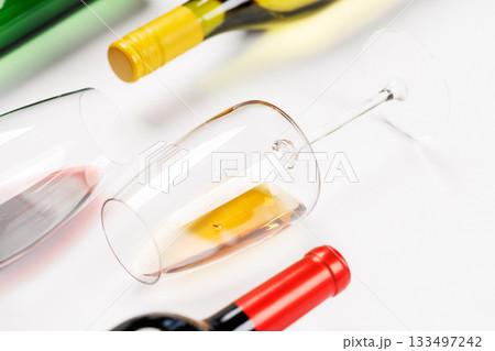 Wine glasses with red and white wine and bottles lying on white background 133497242