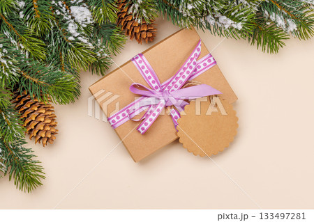 Gift box on snowy fir branches and beige background 133497281