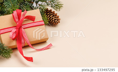 Gift box on snowy fir branches and beige background Gift box on snowy fir branches and beige background 133497295